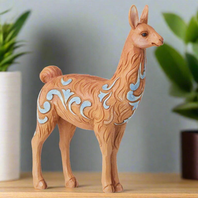 jim shore heartwood creek mini llama figurine on bookshelf with plants