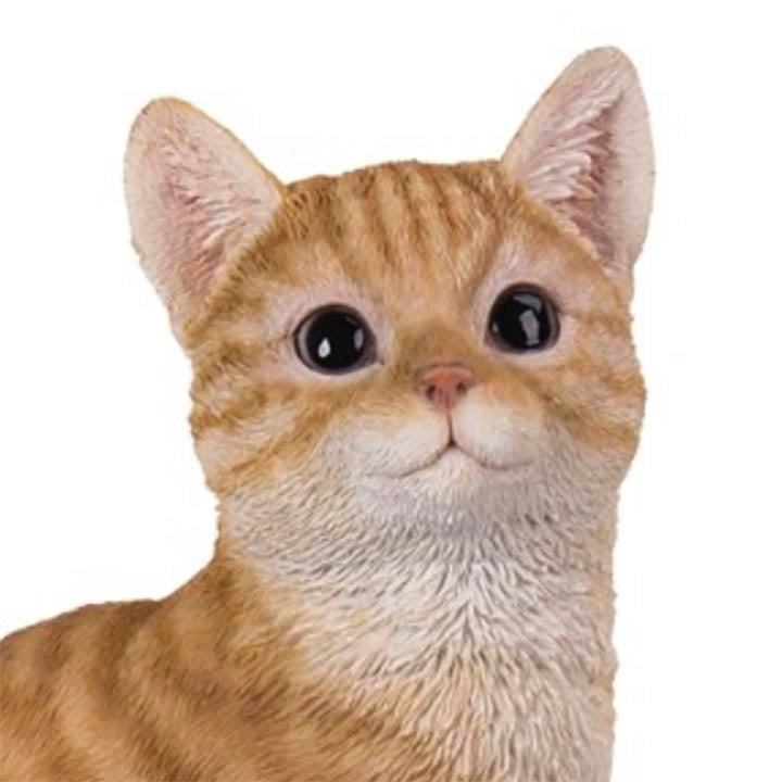 close up face view of orange tabby cat with green eyes shelf sitter figurine